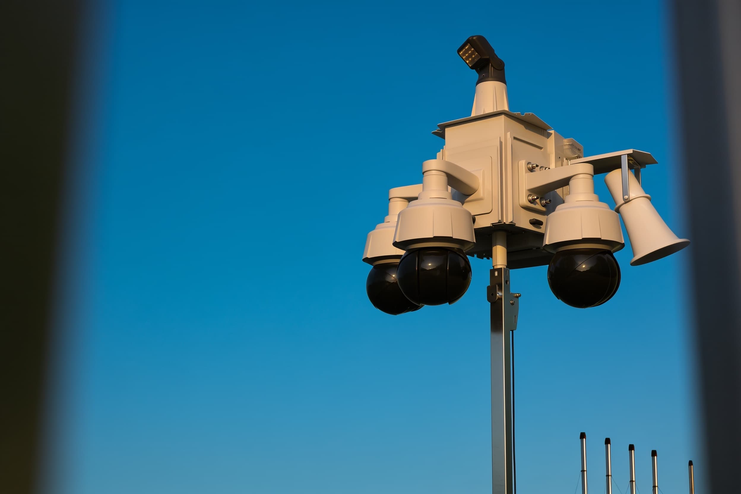 A security camera tight on the head atop the mast against the sky