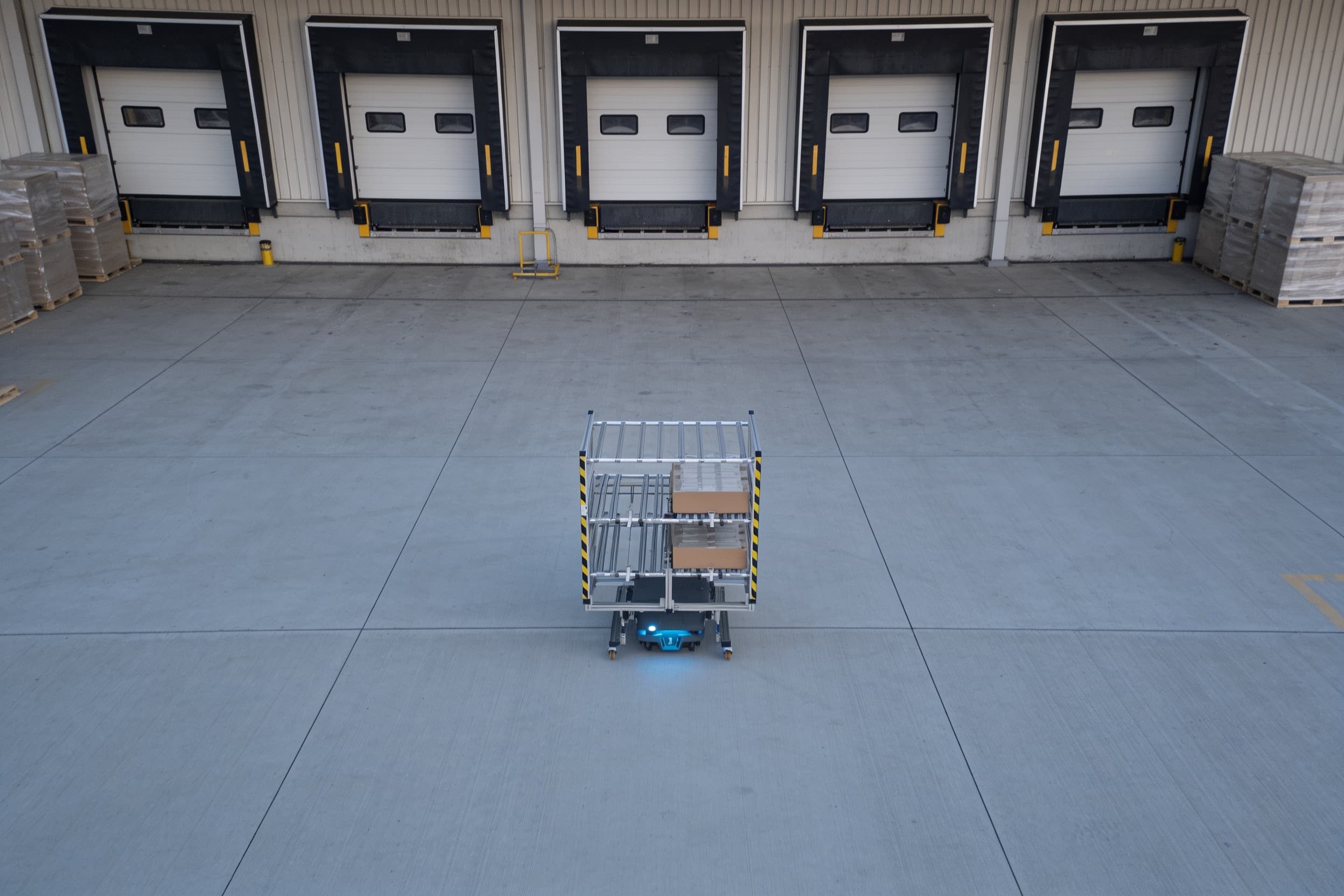 Mobile robot carrying a cart across a warehouse cross-dock